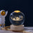 Clear sphere with solar system design, standing next to an astronaut figure on a dark background